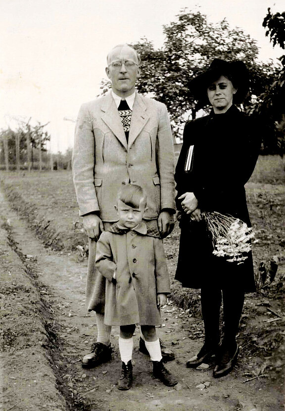 Ein Ehepaar und ein kleiner Junge stehen auf einem Gartenweg auf dem Lindenberg, die Frau trägt einen Blumenstrauß, 1947 