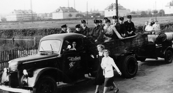 LKW mit angehangener Tragkraftspritze und Feuerwehrleuten auf der Pritsche 